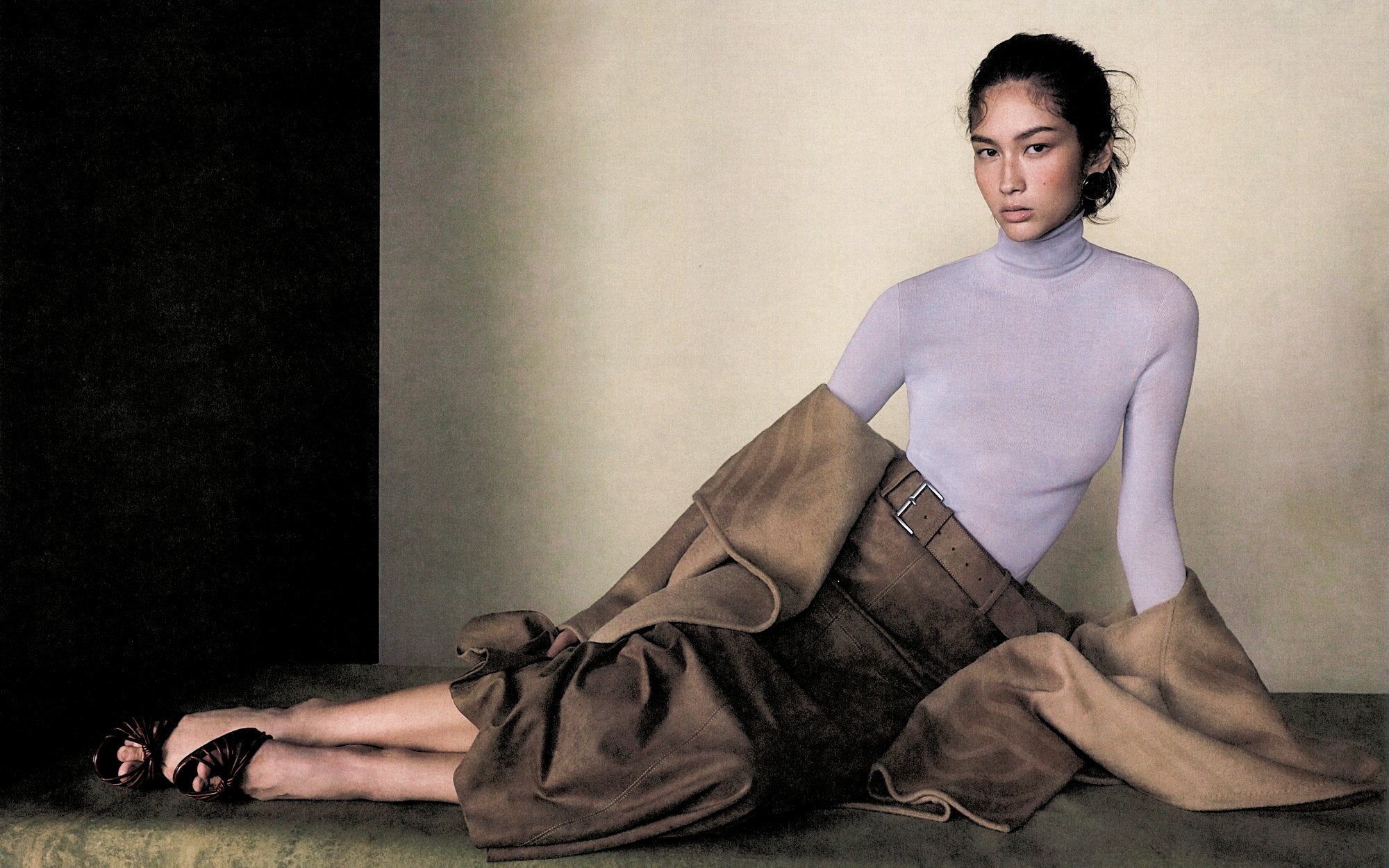 ZHIZHI campaign: a seated figure in lavender knit, brown skirt and camel coat.